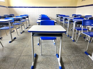 Cadeiras e mesas de uma sala de aula vazia em uma escola p&uacute;blica.