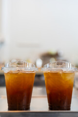 Two plastic takeaway cups of iced black coffee americano. Close up