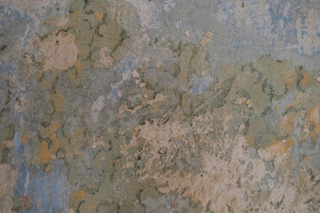 A close-up of a cracked, weathered wall surface with layered, peeling paint in earthy tones. Featuring a blend of blue and green textures, it's perfect for backgrounds or artistic applications.