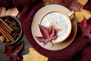 Autumn latte coffee with maple leaf and cozy plaid