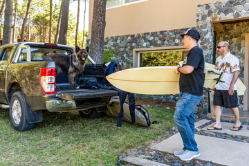 Men and a dog getting ready for a surf trip