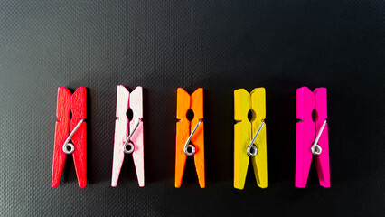 Four colored clothespins on a black background.