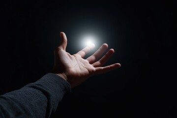 Outstretched hand reaching for light in darkness