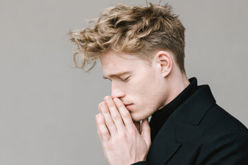 young man with misty eyes and trembling hands lost in daydream stands against clean solid backdrop