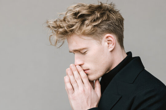 young man with misty eyes and trembling hands lost in daydream stands against clean solid backdrop