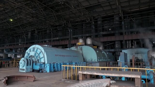 Blue large turbines for electricity production in the middle of the hall at a coal-fired power plant. Pipes with smoke. Outdated polluting energy production technology.