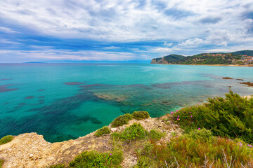 Picturesque view of the coast of the Greek island of Corfu with a beach and turquoise water under a cloudy sky, background or wallpaper for the project