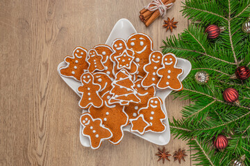 Gingerbread cookies with icing in star shaped plate and Christmas decorations on wooden table, top...