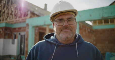 Construction worker in hard hat at building site, determined professional at project location,...