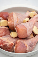 Fresh chicken drumsticks prepared with garlic for marinating before cooking in a home kitchen