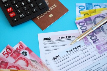 Philippines peso money bills and calculator with tax form on blue. Taxation and accounting concept