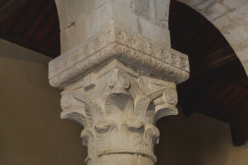 View of an intricately carved stone column, its Corinthian capital adorned with acanthus leaves, standing in silent grandeur, Bominaco, Abruzzo, Italy.