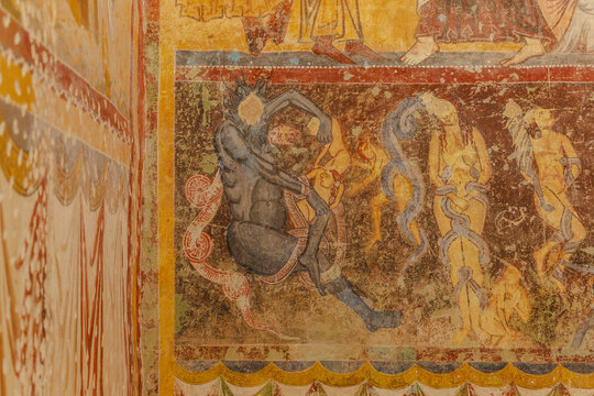 View of ancient walls adorned with vibrant, fading frescoes depicting figures and patterns, a visual story etched in time, Bominaco, Abruzzo, Italy.