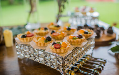 Tartaletas de frutas frescas en bandeja decorativa de cristal para mesa de postres elegante