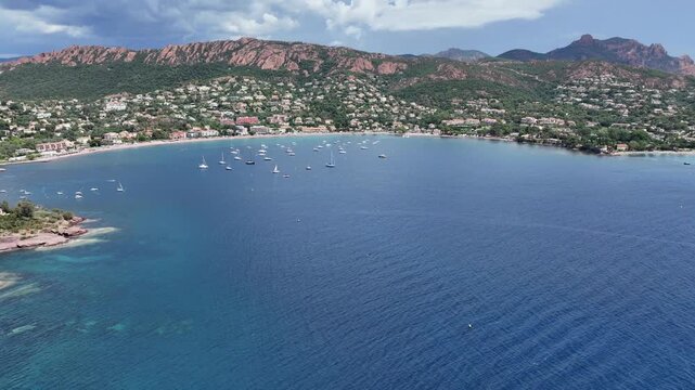 panning left across Agay Bay, French Riviera (C&ocirc;te d'Azur) from  "Phare d'Agay" along coastline to Cap Esterel and Cap Dramont with  "Massif de l'Esterel" in background - 4k aerial video footage