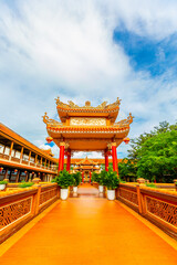 Traditional chinese temple gateway with red columns and ornate roof in lush park setting