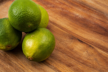 Fresh limes stacked on wooden surface ready for culinary use in vibrant cooking preparations