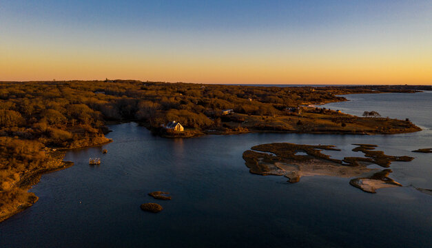 Aerial view of golden sunlight kissing the tranquil waters surrounding Chappaquiddick Island, casting long shadows across the marshy landscape, Martha's Vineyard, Massachusetts, United States.