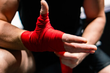 The man ties a red boxing hand wraps around his wrists. Preparing before the box fight. Boxing bandage.