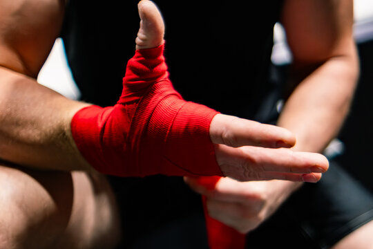 The man ties a red boxing hand wraps around his wrists. Preparing before the box fight. Boxing bandage.