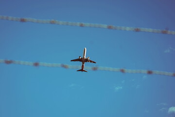 Commercial passenger plane belly or bottom as seen from the ground. Close up telephoto shot, blue sky background, no people