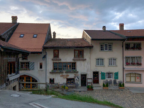 View of a quaint village scene with charming buildings, cobblestone streets, and a cloudy sky creating a serene atmosphere, Gruy&Atilde;&uml;res, Fribourg, Switzerland.