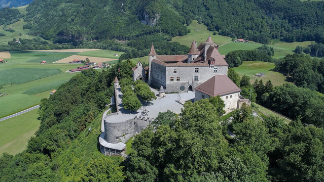 Aerial view of the Gruy&Atilde;&uml;res Castle perched atop a verdant hill, its stone walls and turrets standing proudly against the lush landscape, Gruy&Atilde;&uml;res, Fribourg, Switzerland.