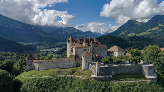Aerial view of the medieval Gruy&Atilde;&uml;res Castle, its stone walls contrasting with the green hillside and the distant, hazy mountains, Gruy&Atilde;&uml;res, Fribourg, Switzerland.