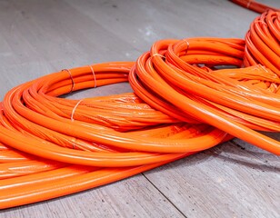 Orange electrical cables coiled on light wood floor