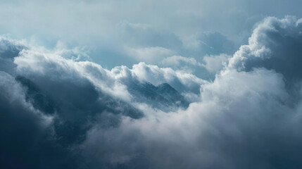 Misty mountain landscape with dramatic clouds swirling around peaks under a moody sky creating a serene and ethereal atmosphere during early morning light.