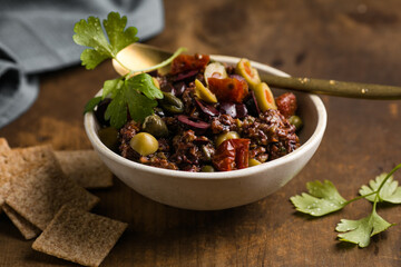 Olive tapenade with herbs and olive oil in a rustic bowl