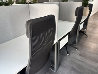 three wheeled office chairs near white clean tables devided by gray partition
