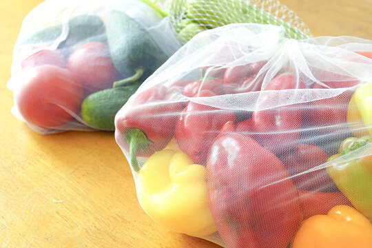 Eco friendly grocery shopping: reusable produce bags filled with peppers, tomatoes, cucumbers. Conscious consumer behavior, clean eating movement, seasonal vegetables, reducing plastic waste concept - Powered by Adobe