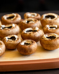 fresh champignon mushrooms on wooden cutting board close up