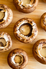 fresh champignon mushrooms on wooden cutting board close up