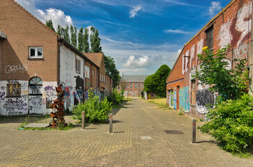 Deserted street in Doel, Belgium showing boarded-up houses decorated with graffiti and street art. The abandoned village represents urban decay and forced depopulation.