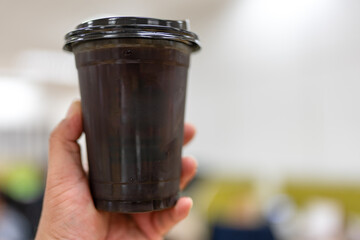 Man hand holding iced black coffee or americano coffee with black lid