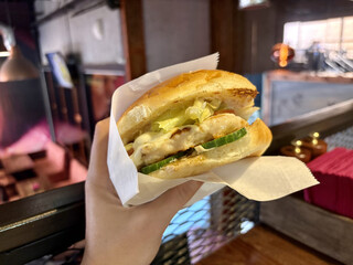 Delicious juicy burger in your hands on the background of a burger joint. POV trend
