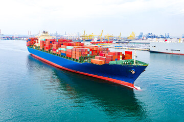 Fototapeta premium Aerial view of international cargo containers ship at industrial import-export port prepare to load containers with big container loader ship vessel at night. global transportation, logistic business