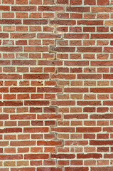 Brick wall with colorful red bricks in various shades. With a repaired crack in the middle.