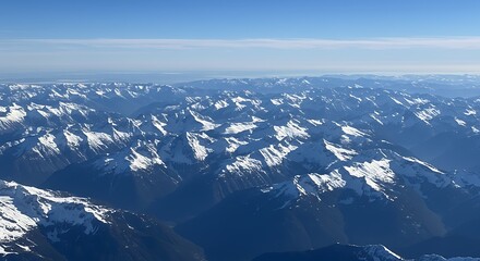Aerial view of snow-covered mountain ranges under clear blue sky