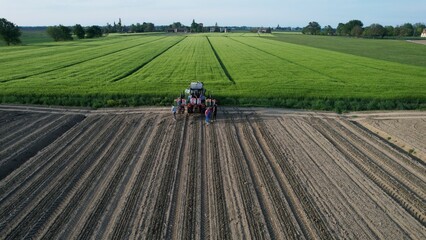 A group of farmers stand proudly in front of their modern tractor after a long day of cultivating fertile fields under a clear blue sky showcasing agricultural technology