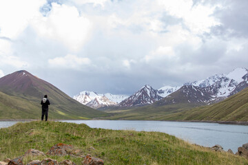 Fototapeta premium A hiker looks over the alpine lake of Kol-Ukok in the high peaks of Kyrgyzstan.