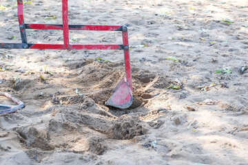 A red shovel is digging into the sand