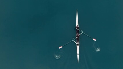 Two athletes rowing a sculling boat on calm blue water, teamwork and endurance in competitive sport. Rowers are practicing sport rowing. Rowers in a racing boat row in slow motion video 120fps. - Powered by Adobe