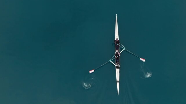 Two athletes rowing a sculling boat on calm blue water, teamwork and endurance in competitive sport. Rowers are practicing sport rowing. Rowers in a racing boat row in slow motion video 120fps.