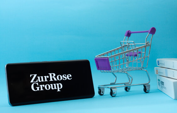 Dhaka, Bangladesh- 03 July 2025: Smartphone with Zur Rose Group logo next to a small shopping cart and boxes against a blue background.