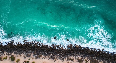 Aerial view of turquoise ocean waves crashing against rocky shoreline