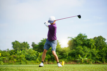 Asian golfer playing golf in morning. He playing a tee off shot.