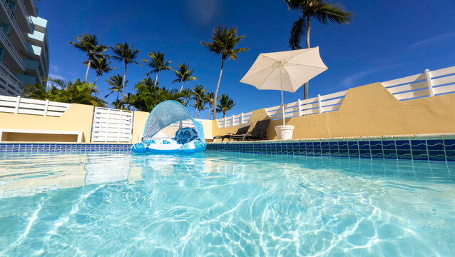 Pool with a pool float, umbrella and palm trees 